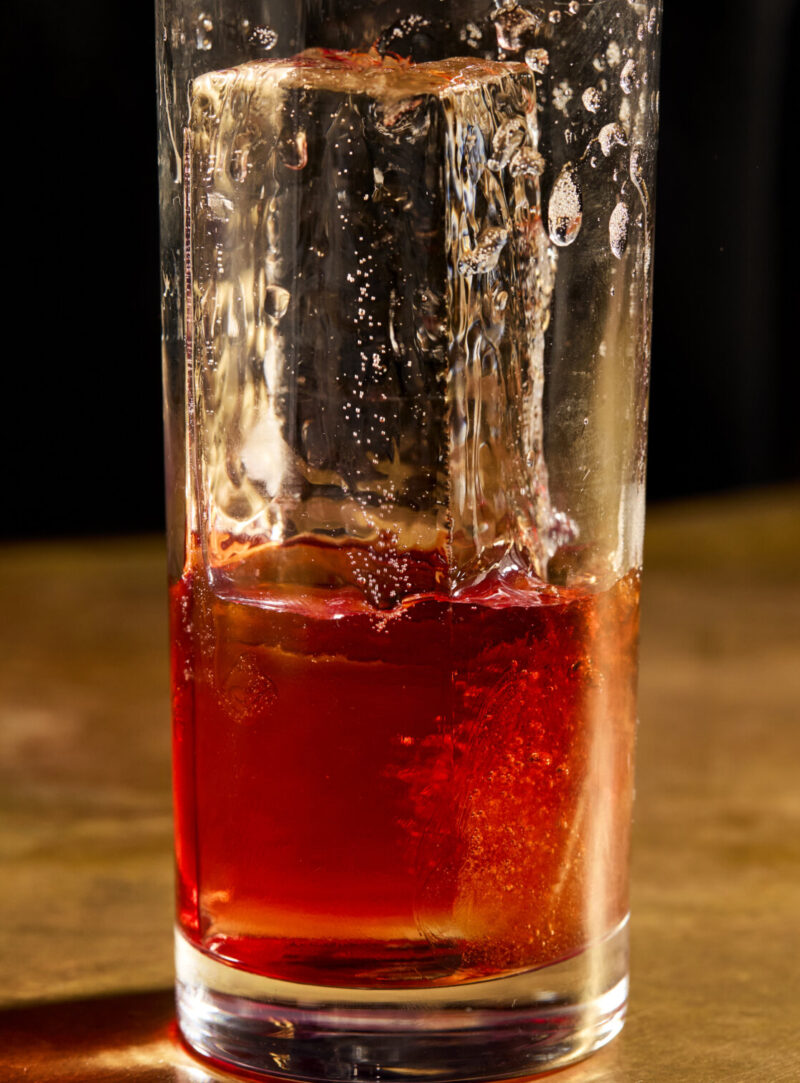 A half-full drink with liquid being poured into it