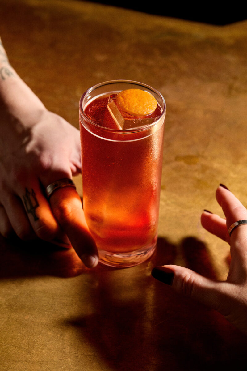 Two hands passing drink across a bar
