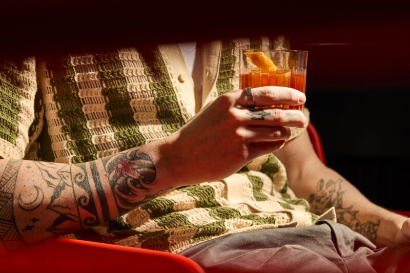 Man holding drink viewed through gap in the chair