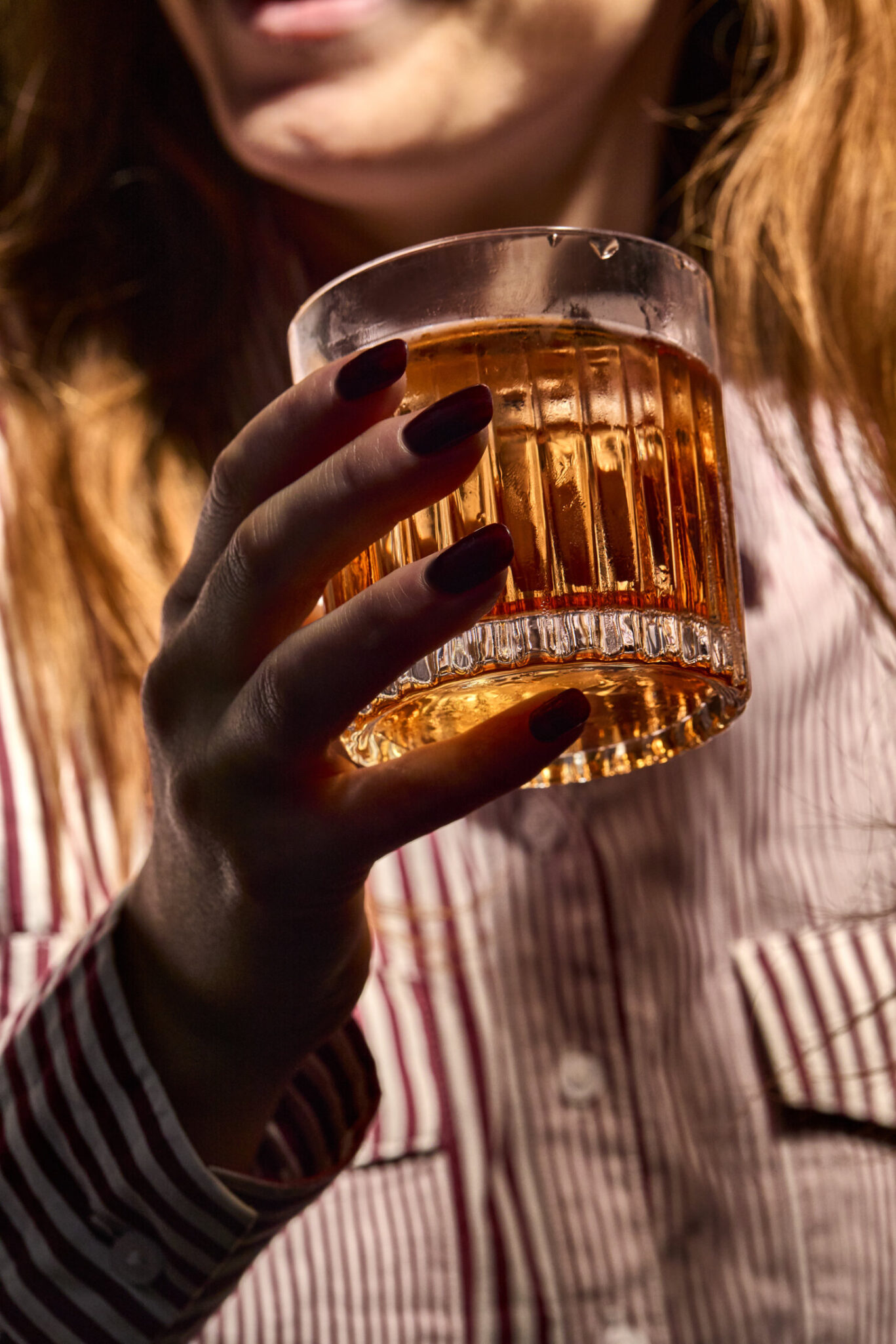 Hand holding negroni with person out of focus behind