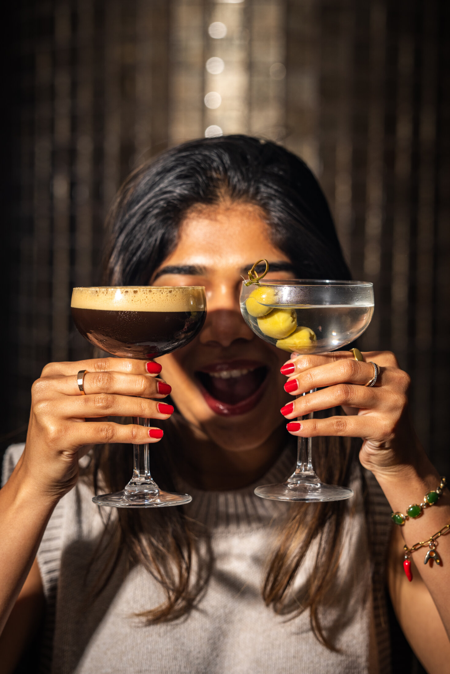 Girl holding two cocktails over eyes